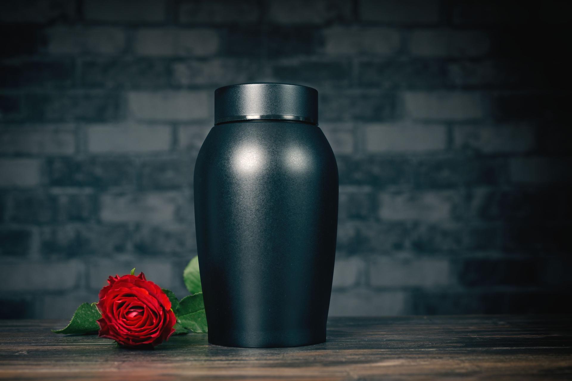 Funeral mourning urn next to a rose flower.